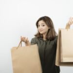 Shot of young female model with craft bags standing over white. High quality photo